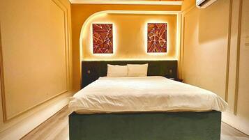 A modern bedroom with a large bed, wooden ceiling, and decorative wall panels.
