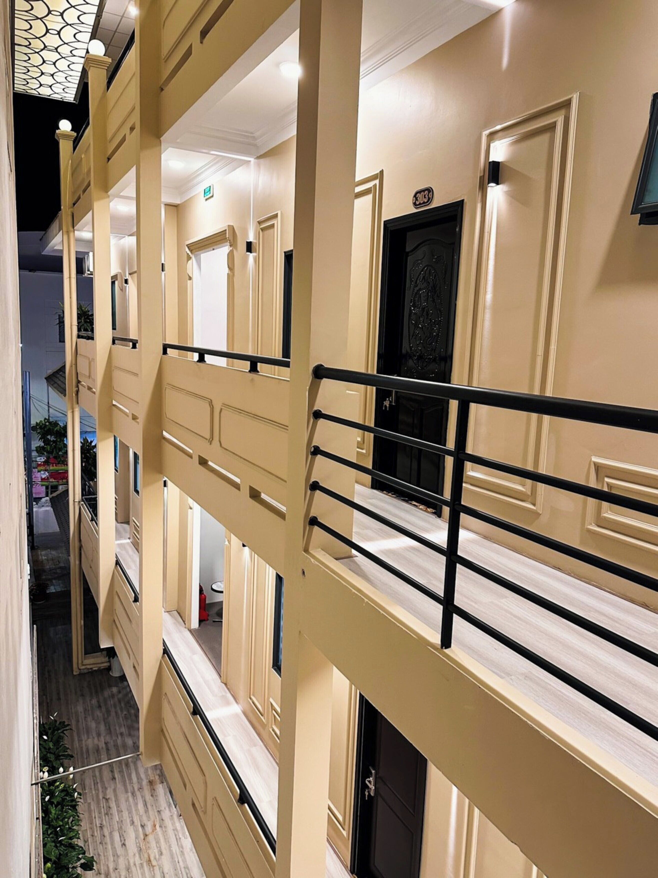 A multi-story hotel with a beige exterior, a black door with a decorative handle, and a balcony railing.