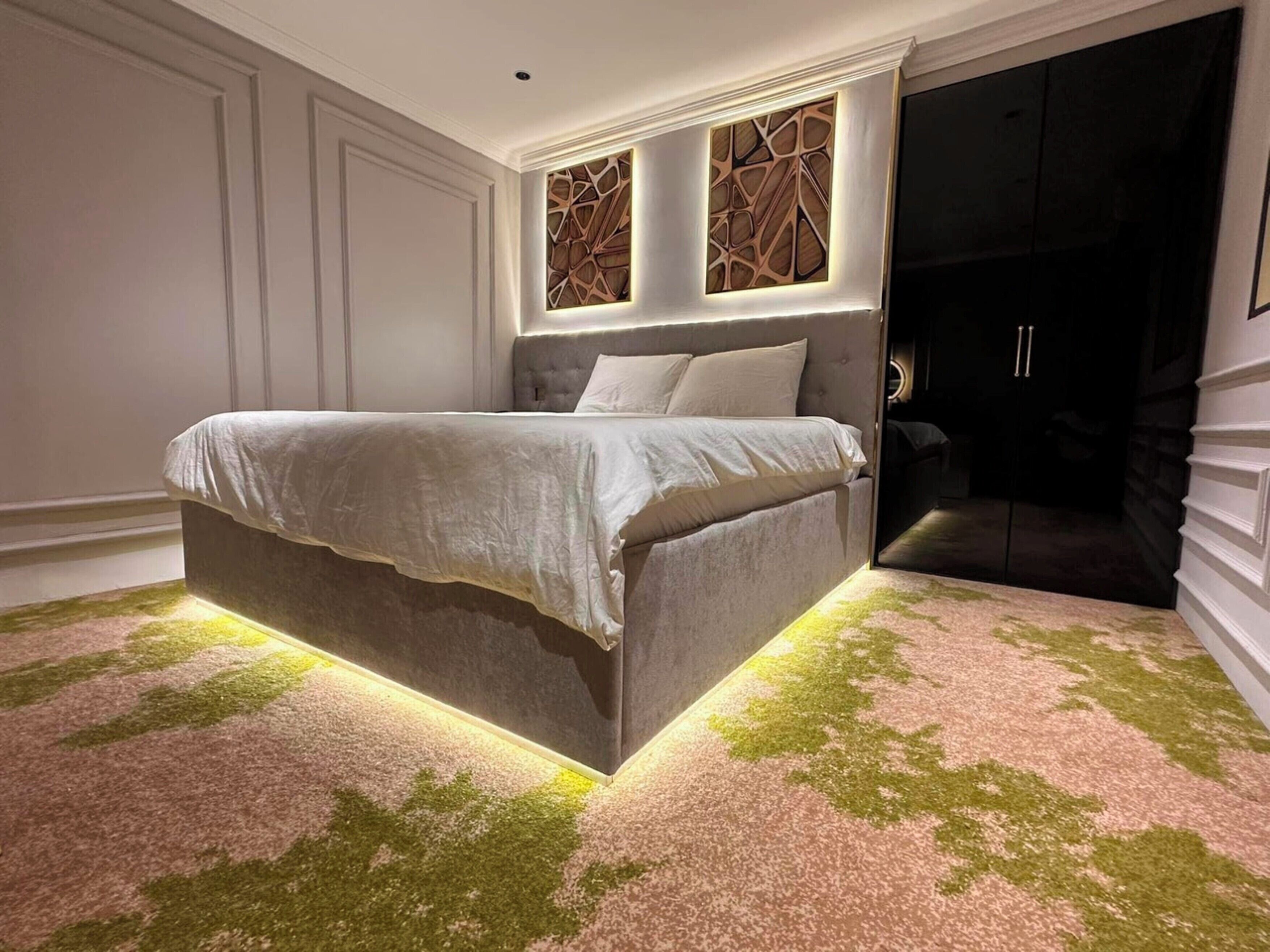 A modern bedroom with a large bed, a built-in headboard, and a unique wall design.
