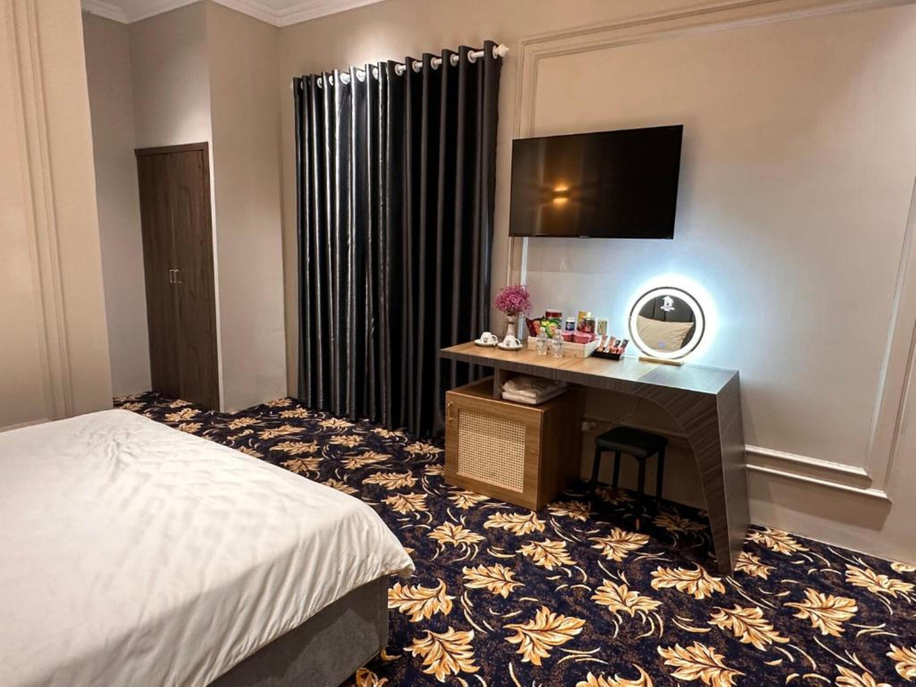 A hotel room with a bed, a desk with a mirror, and a TV.