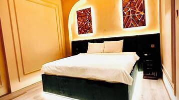 A bedroom with a large bed, wooden ceiling, and two wall-mounted air conditioning units.