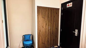 Un corridoio con un armadio in legno, una sedia blu e una porta nera con il cartello ‘divieto di fumo’.