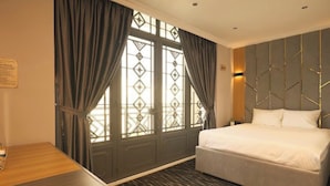 A hotel room with a large bed, a wooden desk, and a window with curtains. - Phuoc Hung 3 (Long Chau)