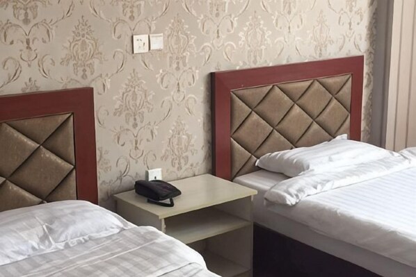 A hotel room with two beds, a small table, and a telephone. - Zhouzhuang Holiday Hostel (Kunshan)