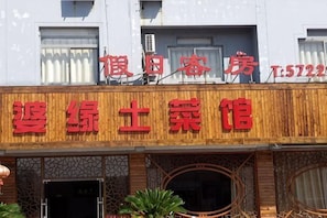 Ein Gebäude mit einer Schautafel, auf der der Name '懒惰客房' und die Telefonnummer 'T:5722' stehen.