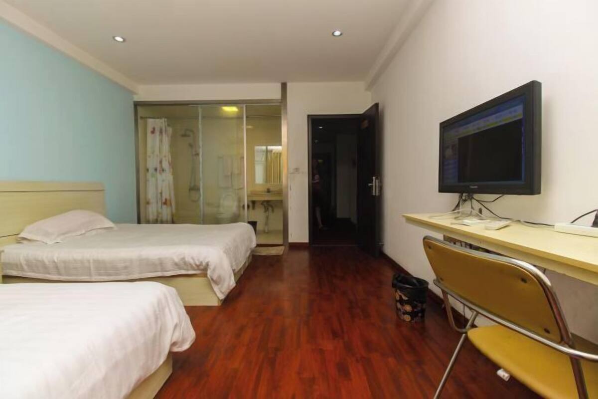 A hotel room with two beds, a desk with a computer, a TV, and a chair.