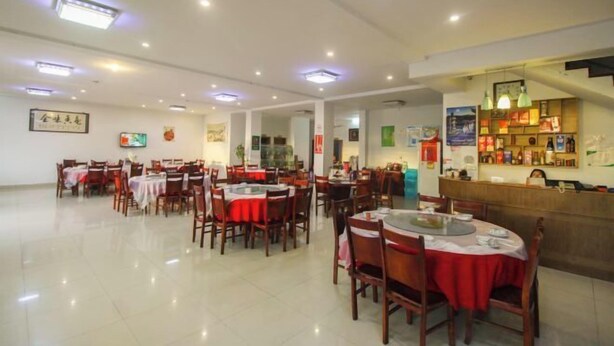 A restaurant with multiple tables and chairs, a counter with a menu, and framed artwork on the walls. - Zhouzhuang Holiday Hostel (Kunshan)