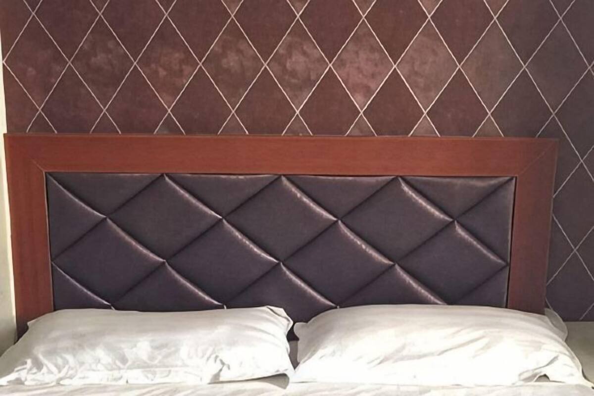 A bed with a padded headboard and two pillows.