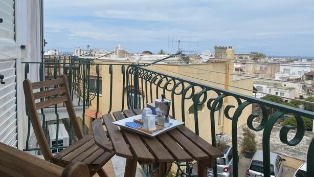 Ein Balkon mit Tisch für zwei Personen, mit Blick auf eine Stadtlandschaft.