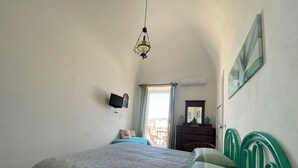 Ein Schlafzimmer mit einem Bett, einem Schminktisch, einem Fernseher und einem Fenster mit Vorhängen.