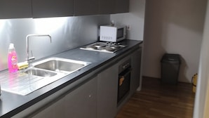 A compact kitchen with a sink, stove, and microwave. - 1 Bed Flat - Sleeps 2 - Parking - Wifi (Bradford)