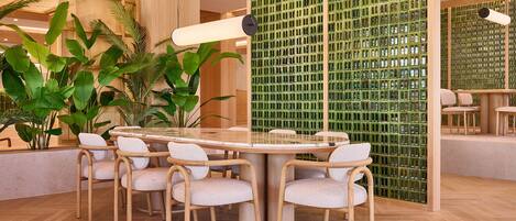 A modern dining area with a round table, six chairs, and a green patterned wall.