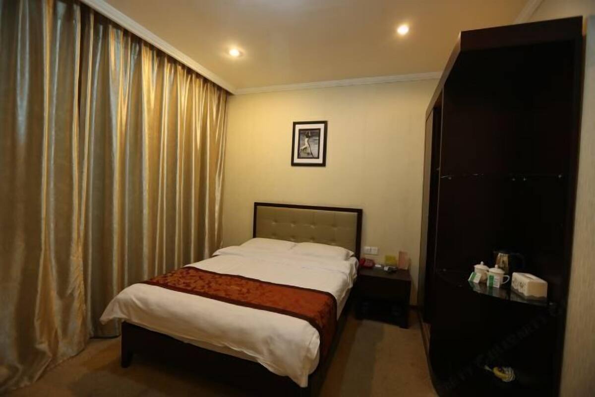 A hotel room with a bed, a nightstand, a wardrobe, and a framed picture on the wall.