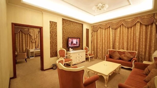 A living room with a television, sofa, armchair, and a small table. - Haidian Resort Hotel (Beihai)