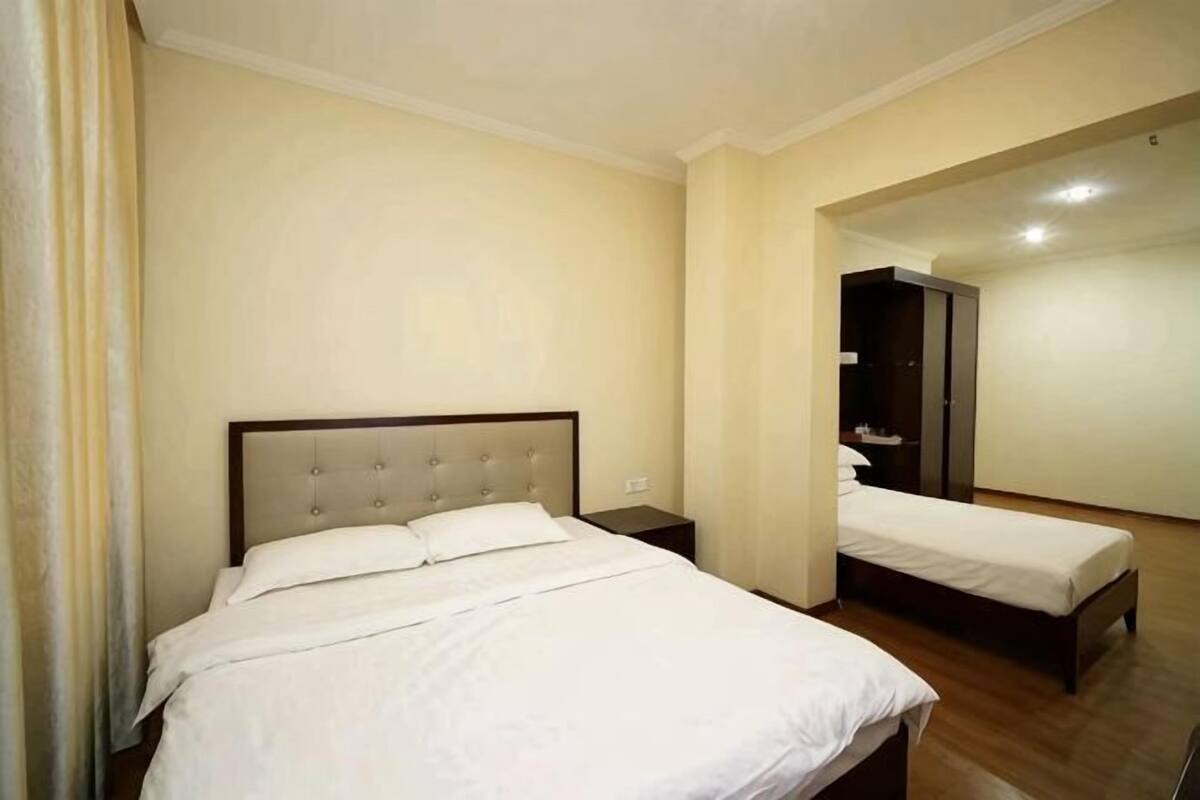 A hotel room with a double bed, a nightstand, a wardrobe, and a mirror.