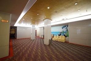 A hotel lobby with a patterned carpet, a reception desk, and a wall with a scenic mural. - Haidian Resort Hotel (Beihai)