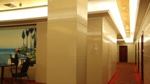 A hotel corridor with a wooden floor, a red carpet, and a painting of a beach scene on the wall. - Haidian Resort Hotel (Beihai)
