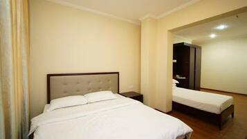 A hotel room with a large bed, a bedside table, a wardrobe, and a mirror.