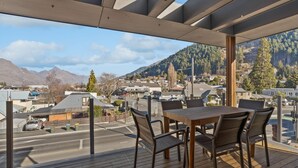 Un balcón con mesa y sillas, con vistas a una calle y montañas.