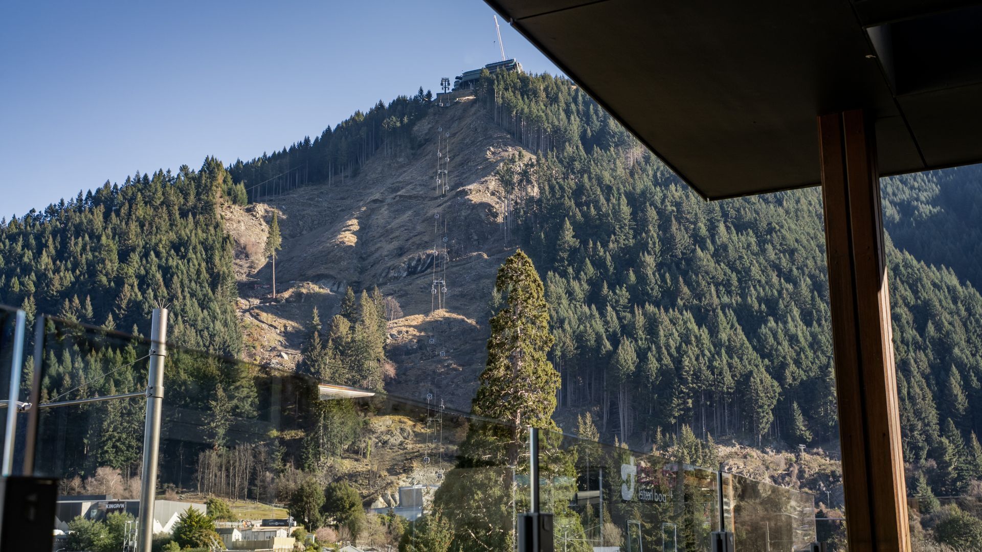 Paisatge de muntanya amb un edifici al cim, envoltat per un bosc dens.