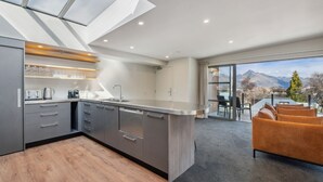 Una cocina moderna con una isla grande, una zona de comedor con vistas a las montañas y un rincón de estar acogedor con un sofá.