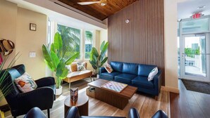 Un salon moderne avec un canapé bleu, une table basse et de grandes plantes vertes.