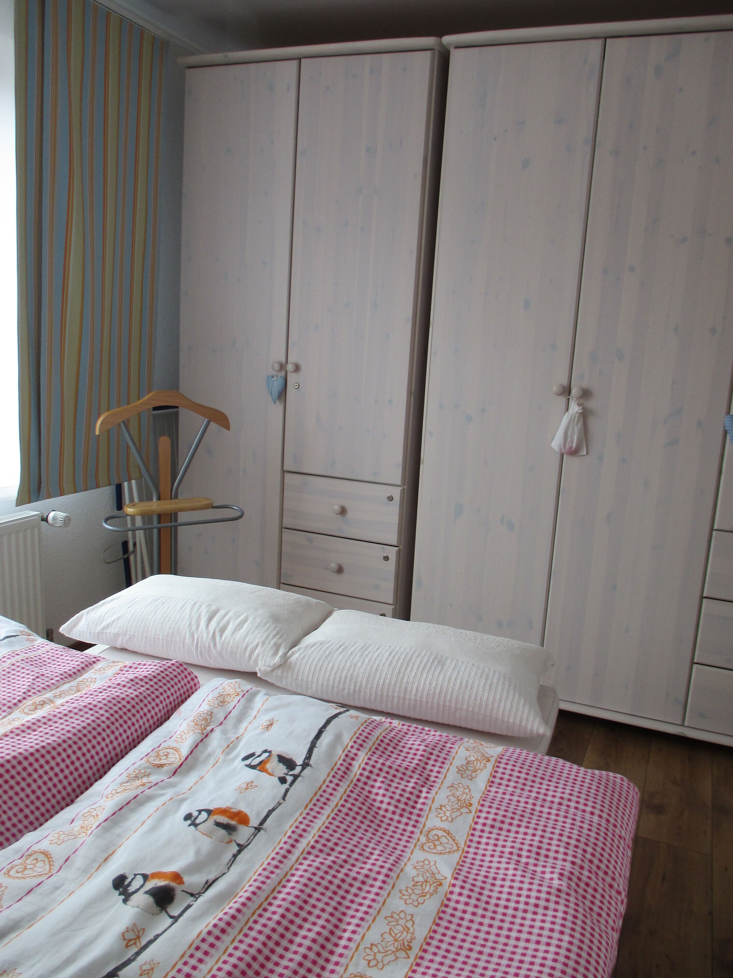 Une chambre à coucher avec un lit, une armoire et un radiateur.
