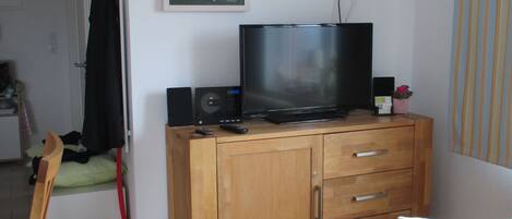 A living room with a wooden cabinet, a television, and a painting on the wall.