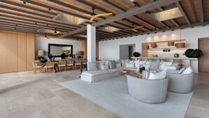 A spacious living area with a large sectional sofa, a dining table with chairs, and a kitchen area with a countertop and cabinets.