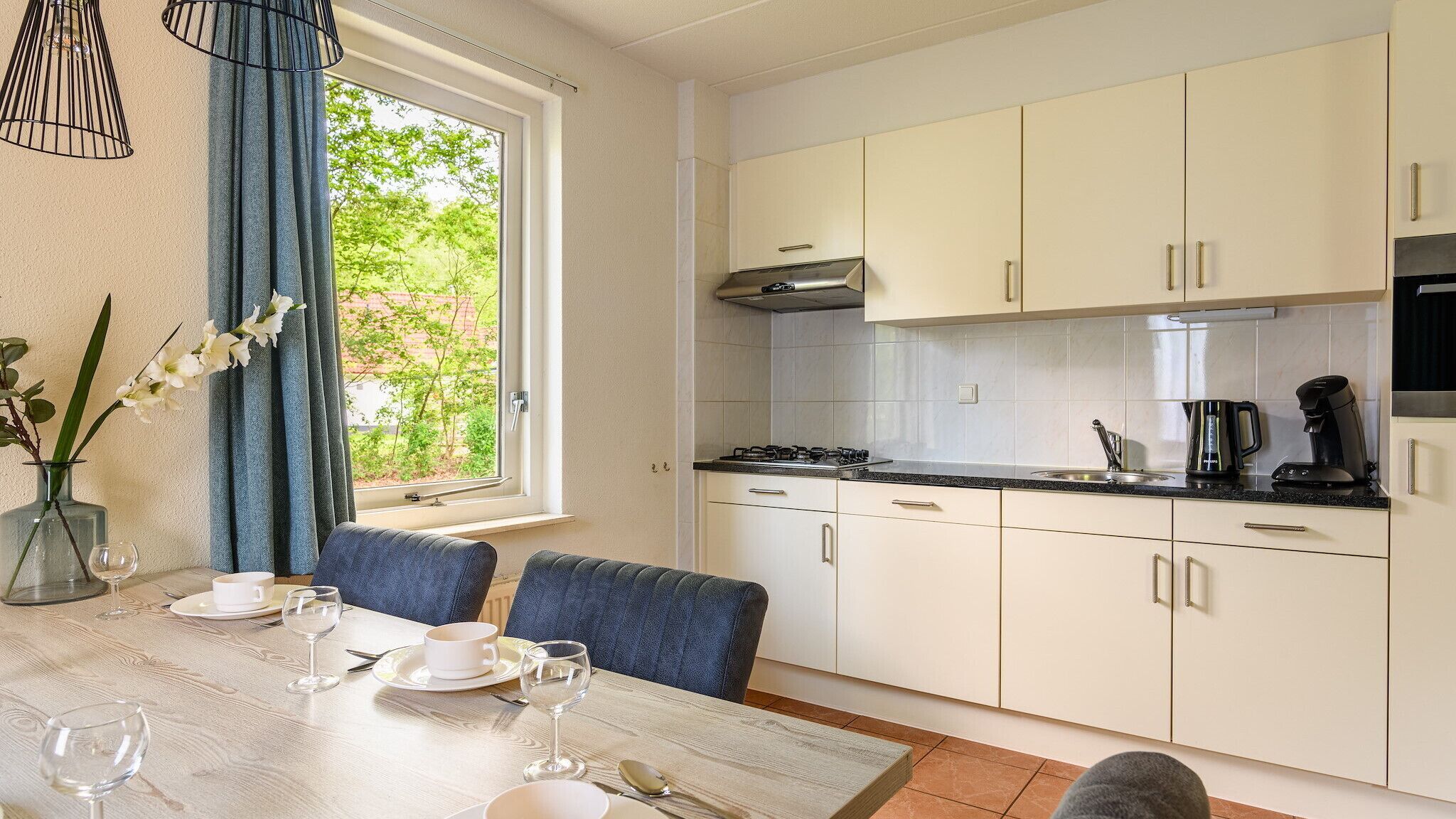 Une cuisine moderne avec des meubles blancs, une cuisinière à gaz et une machine à café.