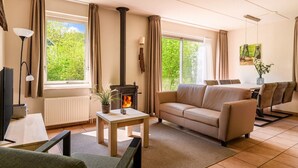 Una sala de estar acogedora con sofá, una mesita, chimenea y un comedor con sillas.