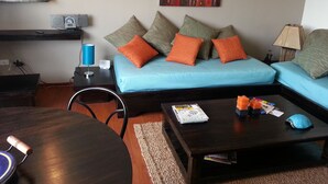 A living room with a sofa, coffee table, and a painting on the wall. - Lovely Suite w/good internet perfect for digital nomads (Quito)