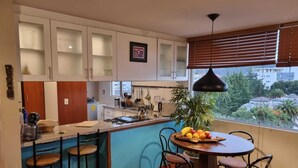 A kitchen with a dining area, a stove, a sink, and a window with blinds. - Lovely Suite w/good internet perfect for digital nomads (Quito)