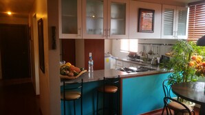 A kitchen with a central island, bar stools, a stove, and a dining table with chairs. - Lovely Suite w/good internet perfect for digital nomads (Quito)