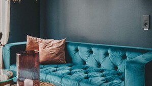 A teal upholstered sofa with two cushions, a glass candle holder with a candle, and a round wooden table with a candle. - 4 Star Holiday Home in Hisings Backa (Hisings Backa)