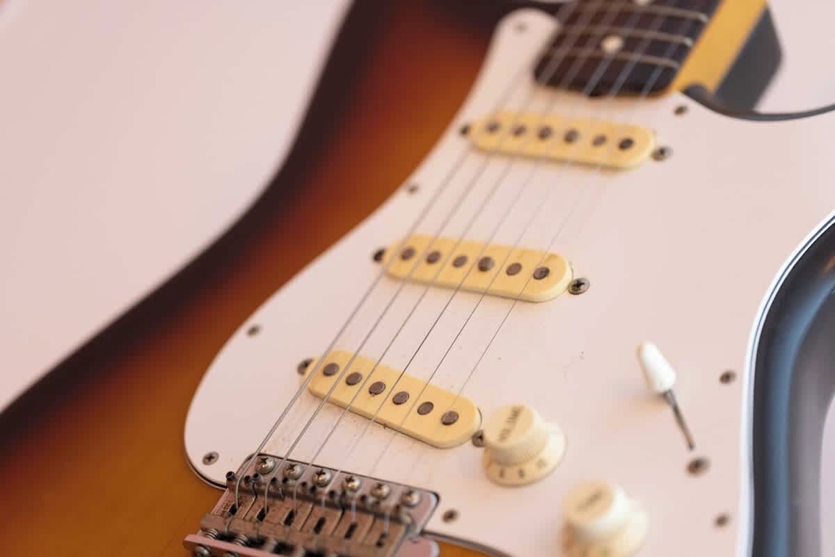 Eine Nahaufnahme des Korpus und Halses einer E-Gitarre, wobei die Tonabnehmer und Regler im Fokus liegen.