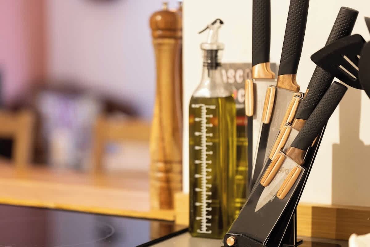 A kitchen counter with a knife block, a pepper mill, and a bottle of oil.