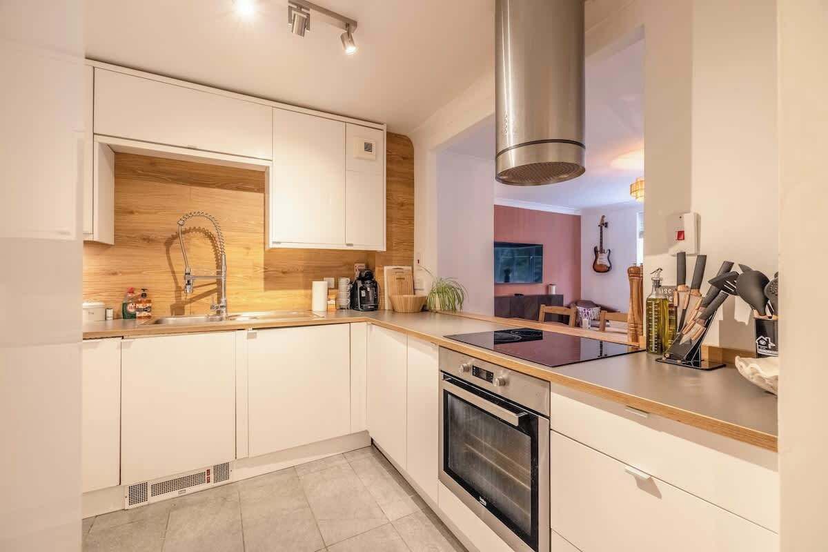 Een moderne keuken met witte kasten, een roestvrijstalen afzuigkap en een inbouwoven.