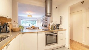 Una cocina moderna con armarios blancos, una campana extractora de acero inoxidable y un horno integrado.