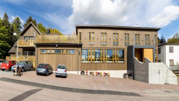 A modern building with a wooden facade, large windows, and a parking area with several cars. - 4 Star Holiday Home in Hisings Backa (Hisings Backa)