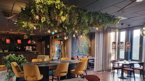 A restaurant with a high ceiling, hanging plants, and modern lighting fixtures. Tables and chairs are arranged for dining. - 4 Star Holiday Home in Hisings Backa (Hisings Backa)