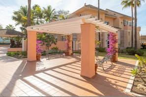 Un espacio al aire libre cubierto con una pérgola, asientos y plantas en macetas.