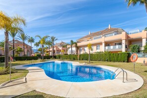 Una piscina rodeada de palmeras y un edificio residencial.