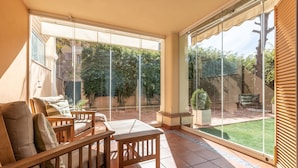 A sunlit patio with a wooden table and chairs, large glass doors leading to a garden. - Mar Bella in Marbella (Marbella)