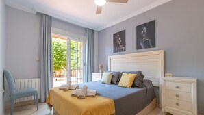 A bedroom with a bed, a nightstand, a chair, and a window with curtains. - Mar Bella in Marbella (Marbella)