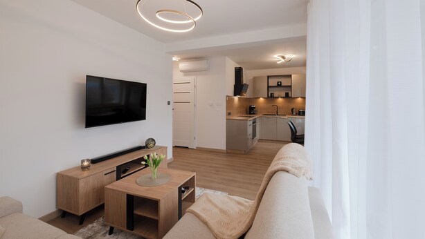 A modern living room with a flat-screen TV, wooden furniture, and a cozy seating area. - Apartamenty Sun & Snow Poniwiec (Ustron)
