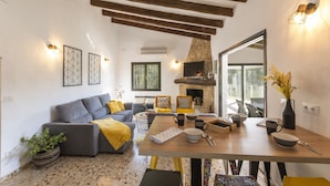 A modern living room with a fireplace, a dining table set with bowls and cups, a sofa with cushions, and a potted plant. - Horizonte in El Capso (Orba)