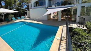 A modern poolside area with a clear blue pool, lounge chairs, and a covered outdoor seating area. - Horizonte in El Capso (Orba)