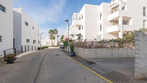 Una calle residencial moderna con edificios blancos, una vía pavimentada y una línea amarilla demarcada.