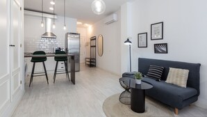 A modern kitchen with a dining area, a sofa, and a coffee table. - Jinetes Holidays in M Laga (Málaga)